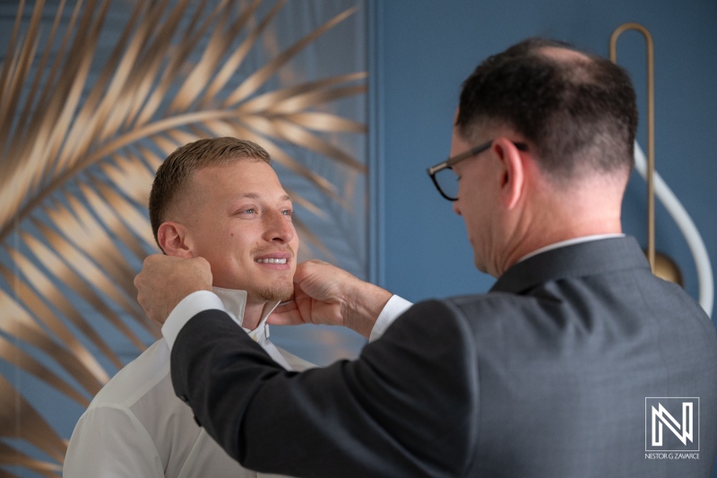 Groom gets ready for wedding at Renaissance Wind Creek Curacao Resort with help from a friend or family member