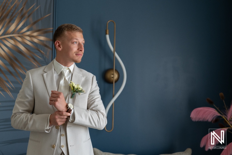 Groom prepares for wedding at Renaissance Wind Creek Curacao Resort with focused expression and classic attire