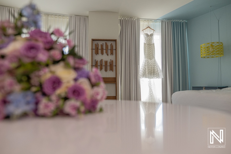 Wedding preparations at Renaissance Wind Creek Curacao Resort with dress hanging and bouquet on table