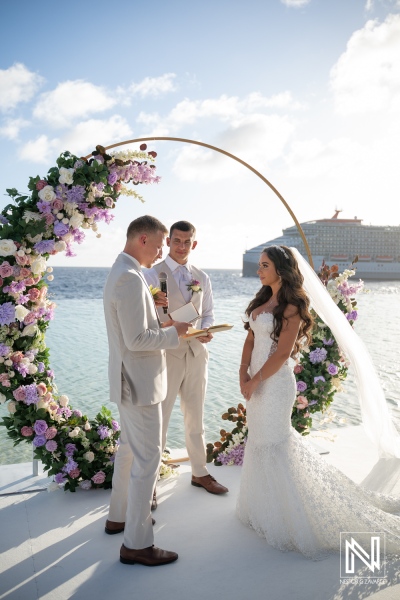 Wedding ceremony by the water at Renaissance Wind Creek Curacao Resort in Curacao with flowers and an officiant