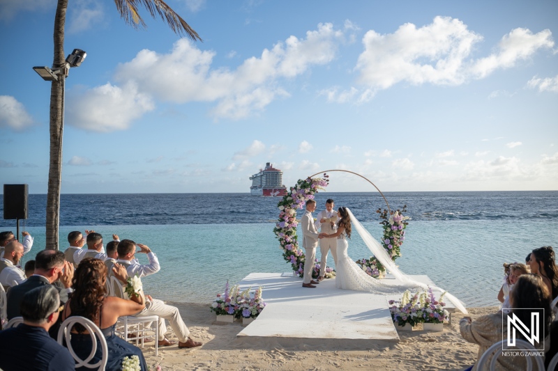 Beautiful wedding ceremony at Renaissance Wind Creek Curacao Resort by the beach with guests and a cruise ship in the background