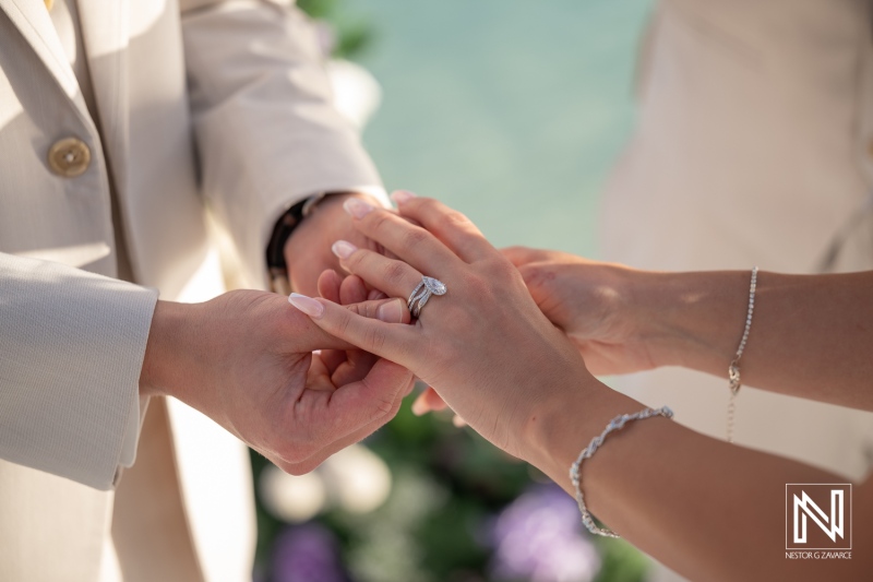 Wedding ceremony at Renaissance Wind Creek Curacao Resort with couple exchanging rings by the sea