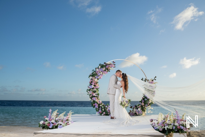 Couple exchanges vows during wedding ceremony at Renaissance Wind Creek Curacao Resort on a sunny day by the ocean