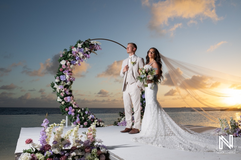 Couple stands together during wedding ceremony at Renaissance Wind Creek Curacao Resort during sunset by the beach
