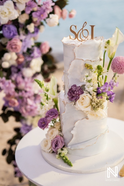 Wedding cake with flowers and decorations at Renaissance Wind Creek Curacao Resort during a wedding ceremony by the beach