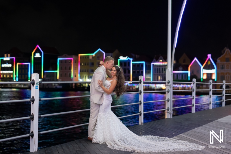 Couple celebrates wedding at Renaissance Wind Creek Curacao Resort near colorful waterfront buildings at night