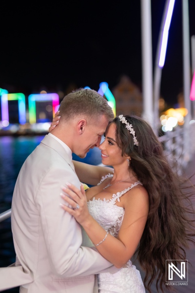 Couple celebrates wedding at Renaissance Wind Creek Curacao Resort by night with colorful lights in the background