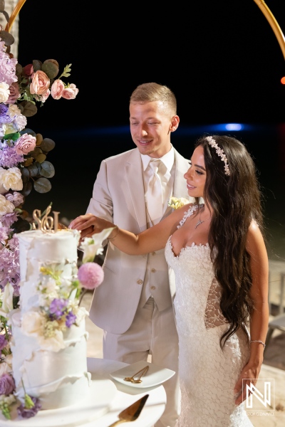 Couple celebrates wedding at Renaissance Wind Creek Curacao Resort with cake cutting at night by the water