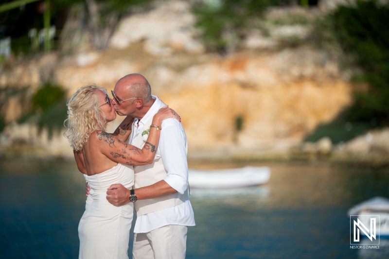 Couple shares a kiss during their wedding ceremony at Daaibooi Beach in Curacao under a clear sky