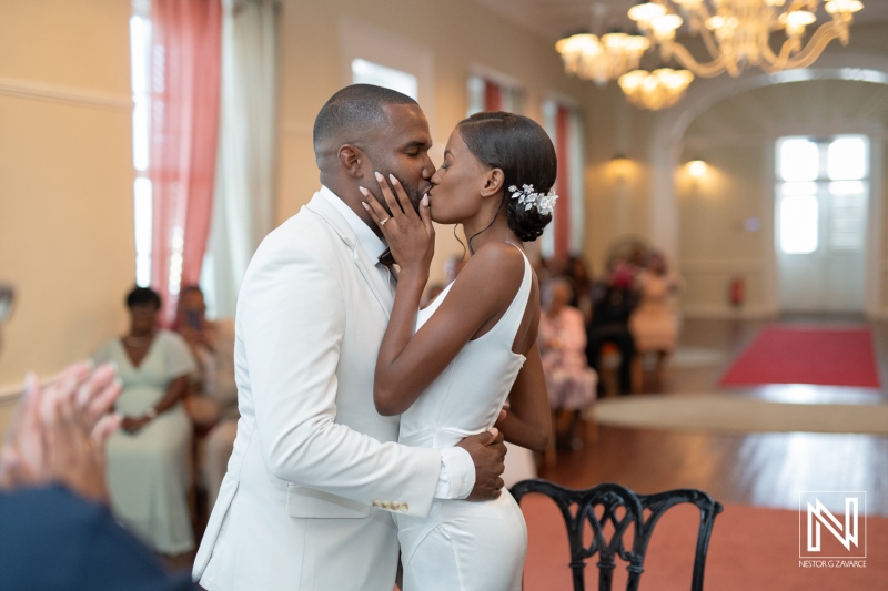 A couple shares a romantic kiss during their wedding ceremony in an elegant venue filled with love and joy in the afternoon light