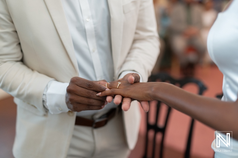 A couple exchanges wedding rings during their intimate ceremony held in a beautifully decorated venue in the late afternoon light