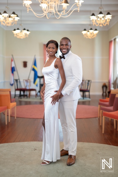 Elegant couple in white attire celebrating their wedding reception in a stylish hall adorned with flags and chandeliers during a daytime event