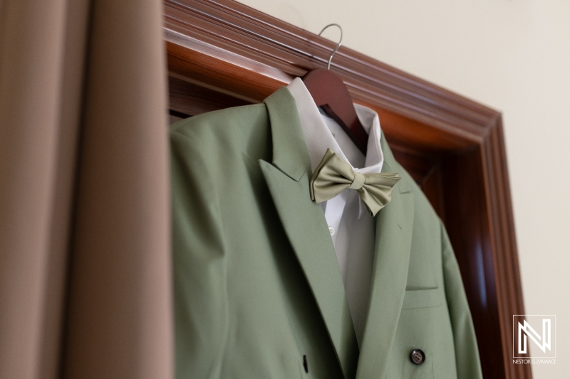 Elegant green suit with bow tie displayed in a doorway, showcasing formal attire preparation for a special event or celebration in a stylish setting