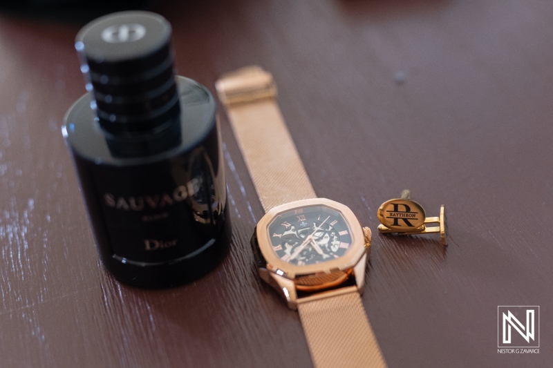 Elegant gold watch, fragrance, and cufflink arranged on a wooden surface, showcasing luxury accessories in a stylish setting