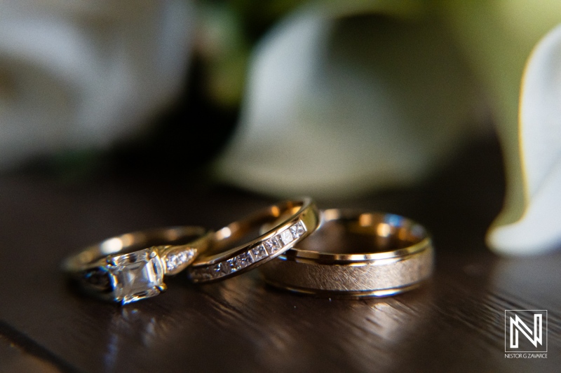 Exquisite wedding rings displayed on a wooden surface with soft floral accents, showcasing detailed craftsmanship and elegance in a romantic setting