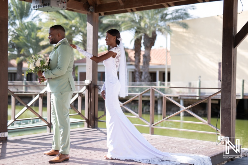 A joyful couple exchanges heartfelt vows under a wooden gazebo in a sunny outdoor venue surrounded by palm trees during a summer wedding ceremony