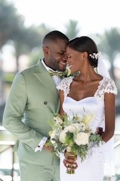 A couple embraces during their romantic wedding ceremony in a sunny outdoor venue surrounded by palm trees and lush greenery in a warm atmosphere