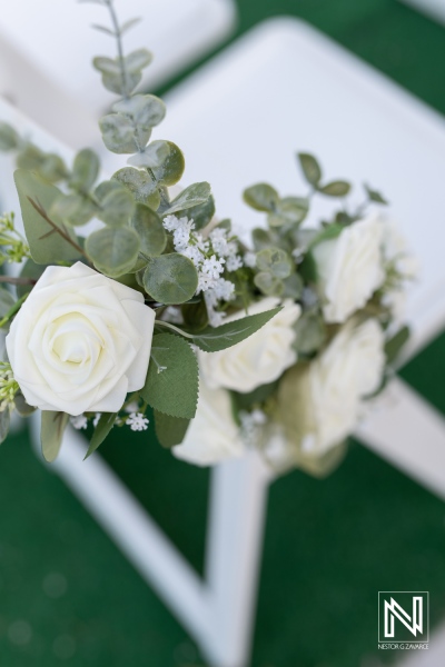 Bouquet of white roses and greenery elegantly arranged on a chair at an outdoor wedding ceremony in sunny weather