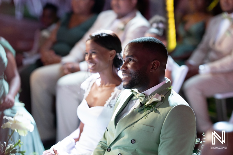 A joyful couple shares smiles during their wedding ceremony in a beautifully decorated venue, surrounded by friends and family on a sunny day