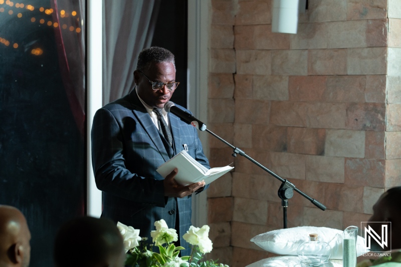 A distinguished speaker reading at a formal event in an elegant venue during the evening, captivating the audience with heartfelt words and reflections