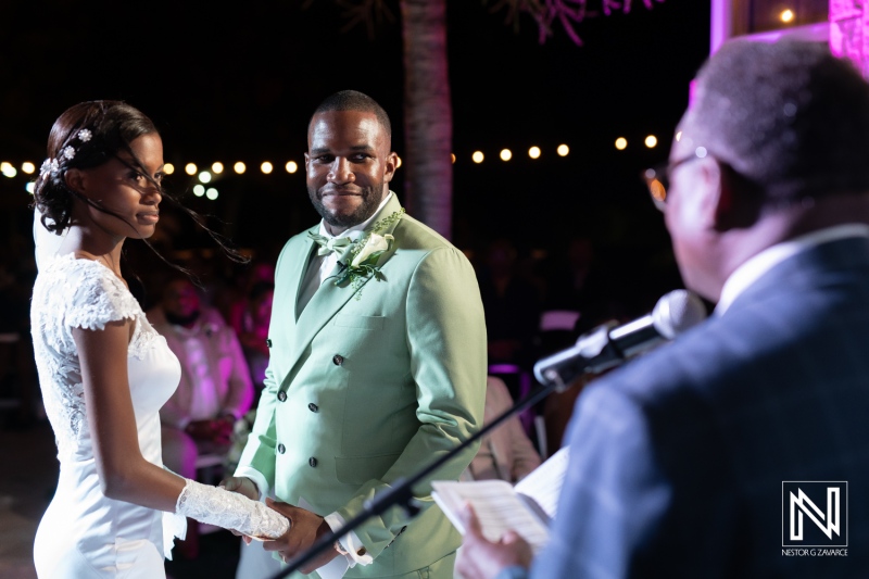 A couple exchanges vows during an outdoor wedding ceremony under twinkling lights in a romantic garden setting