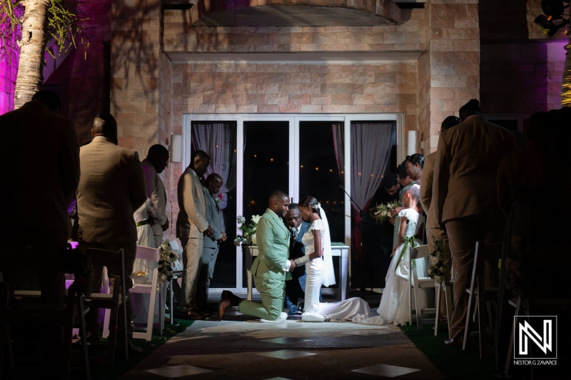 A joyful wedding ceremony unfolds under soft purple lights in an elegant venue as a couple exchanges vows in front of their loved ones and wedding party