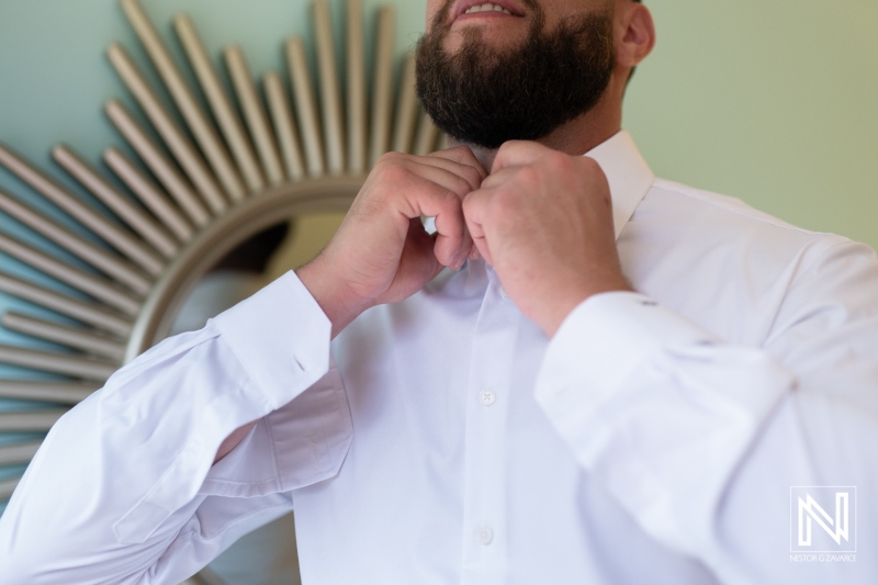 Groom adjusts his collar while preparing for a wedding at Sunscape Curacao Resort in Curacao under bright Caribbean light