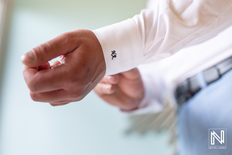 Groom preparing for wedding at Sunscape Curacao Resort with focused attention on cufflink detail