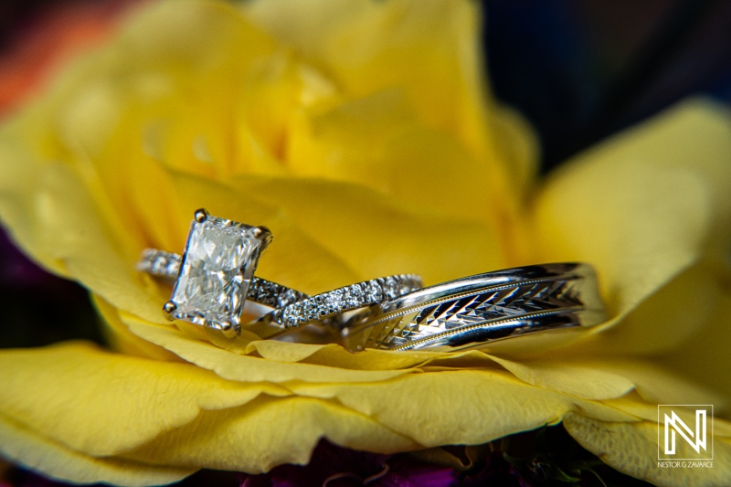 Beautiful wedding rings displayed on a vibrant yellow rose at Sunscape Curacao Resort during a romantic wedding ceremony