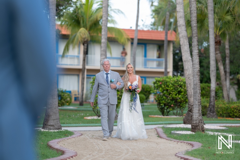 Stunning wedding in Curacao at Sunscape Curaçao Resort with bride and father walking down the sandy path surrounded by palm trees