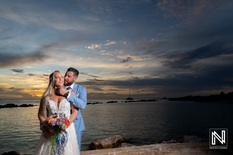 Couple celebrates their wedding at Sunscape Curacao Resort under a stunning sunset sky while enjoying the beautiful ocean backdrop