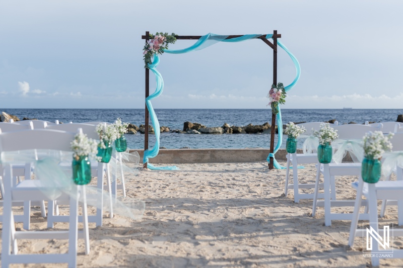 A Beautiful Beach Wedding Setup With Floral Decorations and Turquoise Accents on a Sandy Shore During a Clear Day