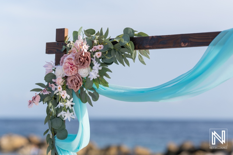 Beautiful Floral Arrangement With Sheer Fabric Draping at a Beachside Wedding Altar During a Sunny Day