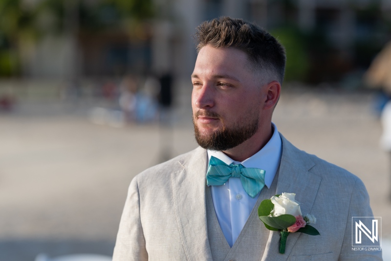 A Groom Enjoying a Sunny Beach Wedding Celebration With a Stylish Suit, Bow Tie, and Floral Boutonniere During the Afternoon Hours by the Ocean