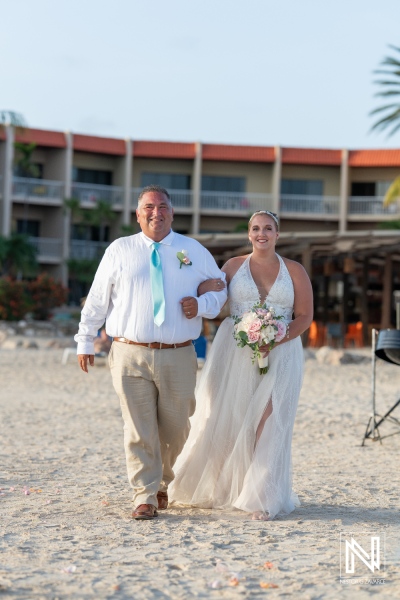 A Father Walks His Daughter Down the Beach Aisle During a Sunset Wedding Ceremony at a Tropical Resort, Creating a Beautiful and Emotional Moment Shared With Family and Friends