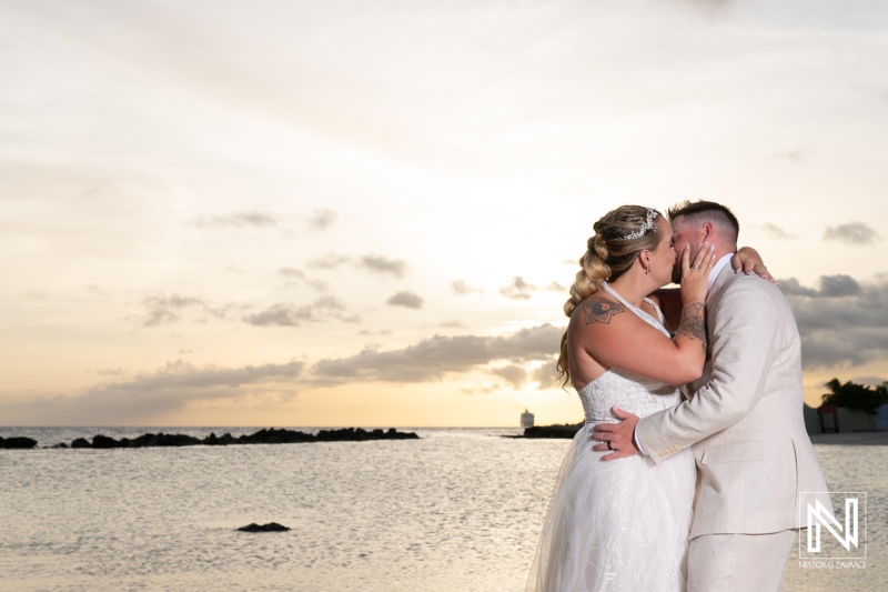 A Newlywed Couple Kisses at Sunset Near a Tranquil Beachfront, Capturing a Moment of Love and Joy During Their Wedding Celebration in a Picturesque Coastal Setting