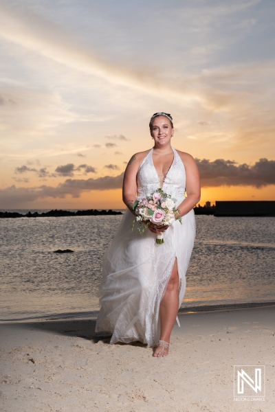 A Bride Walks Confidently Along the Beach at Sunset, Holding a Bouquet of Flowers While Wearing a Stunning White Gown and Enjoying the Picturesque View