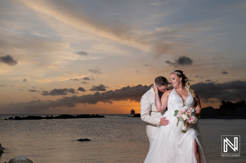 A Beautiful Sunset Wedding Moment on the Beach With a Bride and Groom Embracing Against a Colorful Sky Near the Ocean\'s Edge