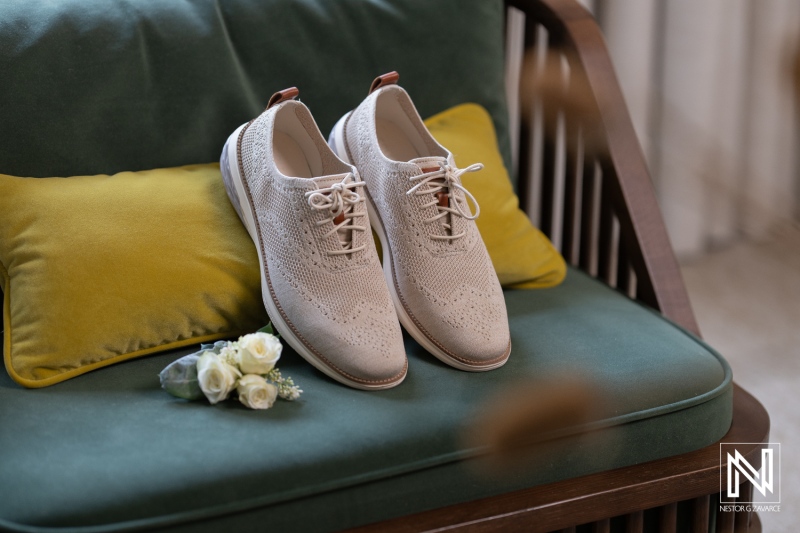 Elegant wedding shoes and floral arrangement on a cozy couch at Renaissance Wind Creek Curacao Resort during sunset