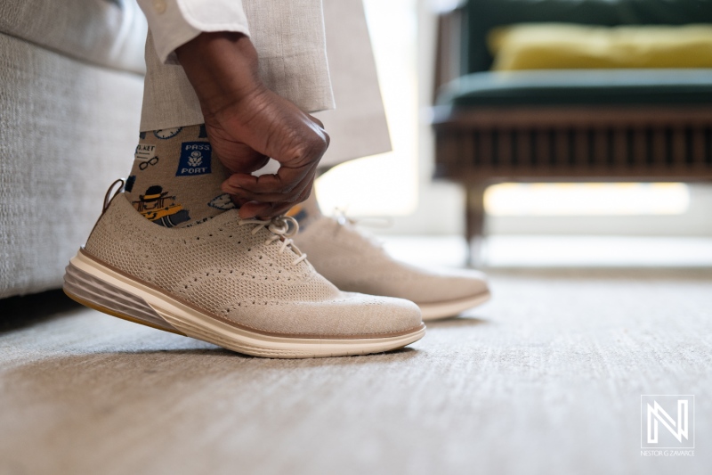 Groom getting ready for wedding while putting on stylish shoes in the elegant setting of Renaissance Wind Creek Curacao Resort at sunset