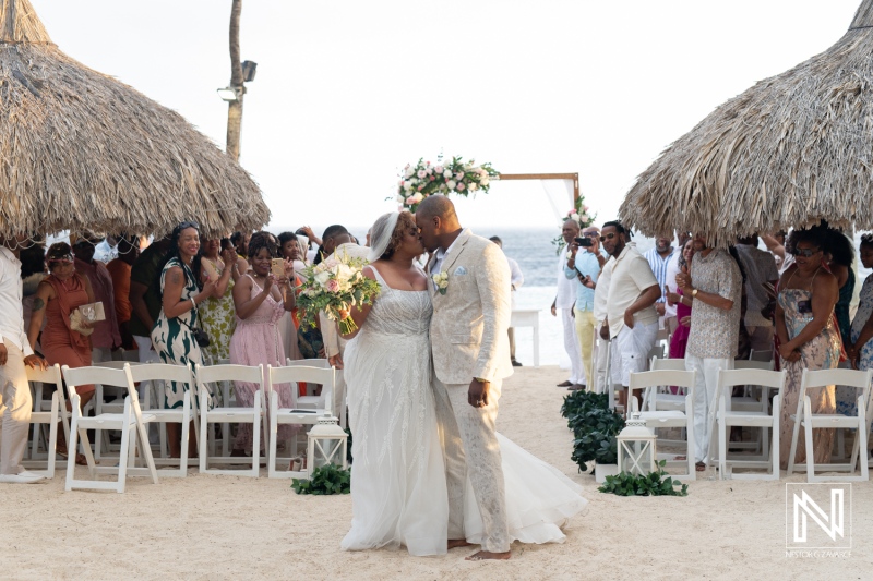 Beautiful wedding ceremony at Renaissance Wind Creek Curacao Resort during a stunning sunset on the beach with joyful guests celebrating the couple's love