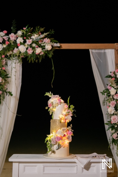 Sweetheart wedding setup with floral decorations and a stunning cake at sunset on the beach in Curacao