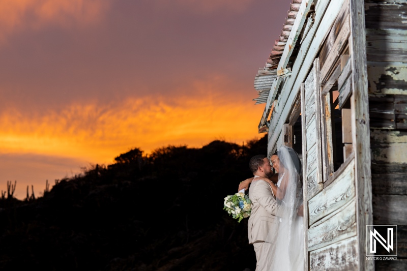 Couple shares a romantic kiss at sunset during their wedding ceremony at Playa Hunku in Curacao