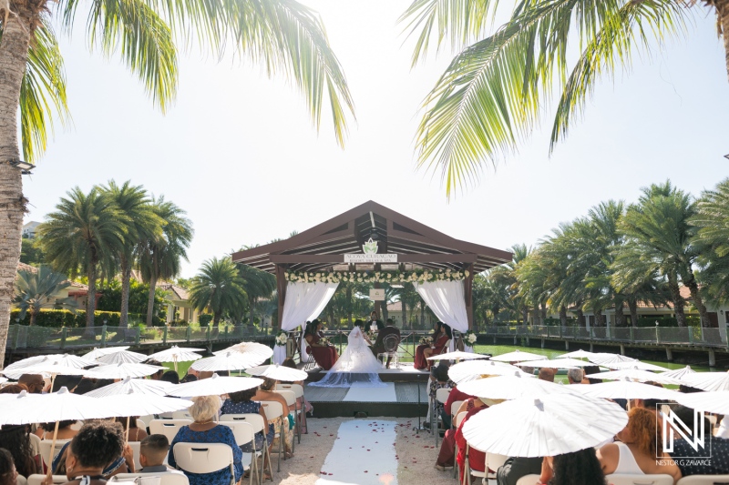 Wedding ceremony at Acoya Curacao Resort with vibrant surroundings and guests under palm trees