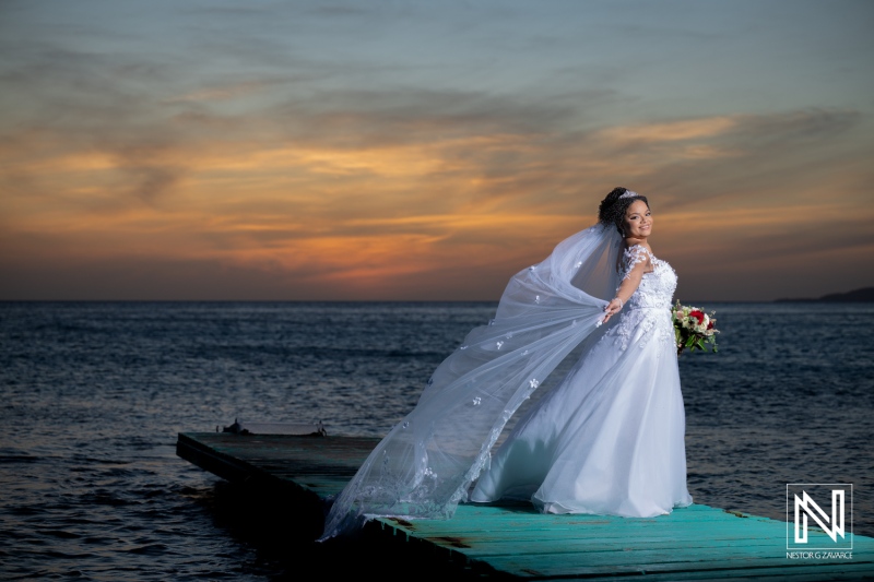 Stunning bride poses elegantly near the ocean during sunset at Acoya Curacao Resort wedding celebration