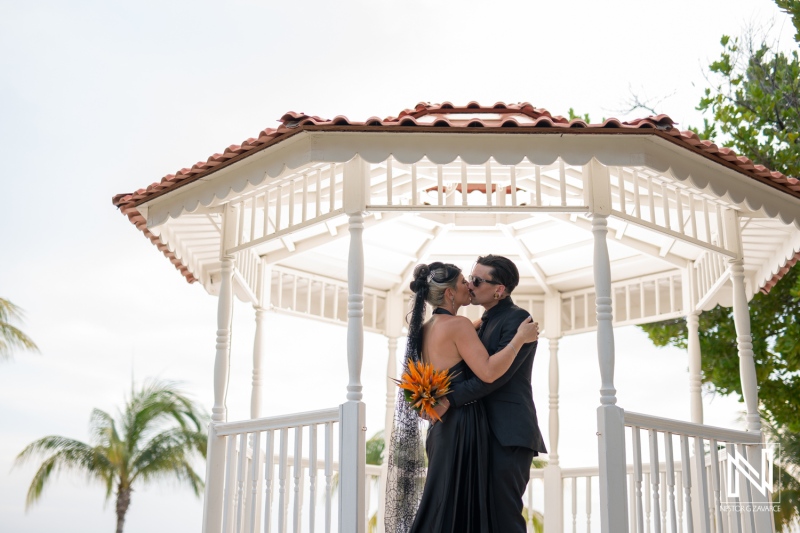 Couple sharing a kiss under a gazebo at Sunscape Curacao Resort during a Halloween wedding celebration