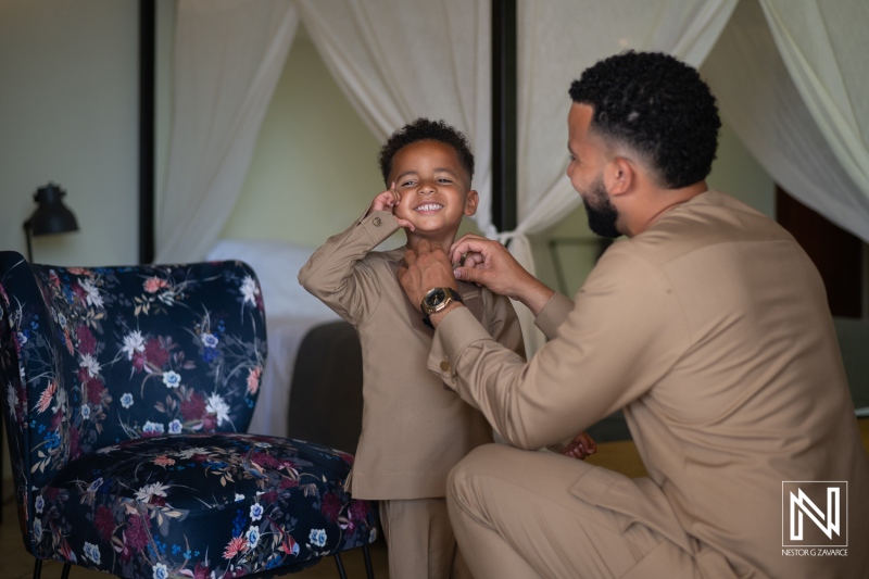 Father Helps His Son Get Ready in a Cozy Room, Both Smiling With Joy as They Share a Special Bonding Moment During a Family Occasion