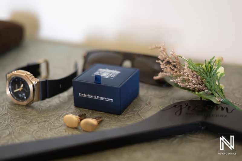 Accessories Arranged Neatly on a Decorative Surface Featuring a Watch, Cufflinks, Sunglasses, a Flower, and a Small Blue Box in a Stylish Setting