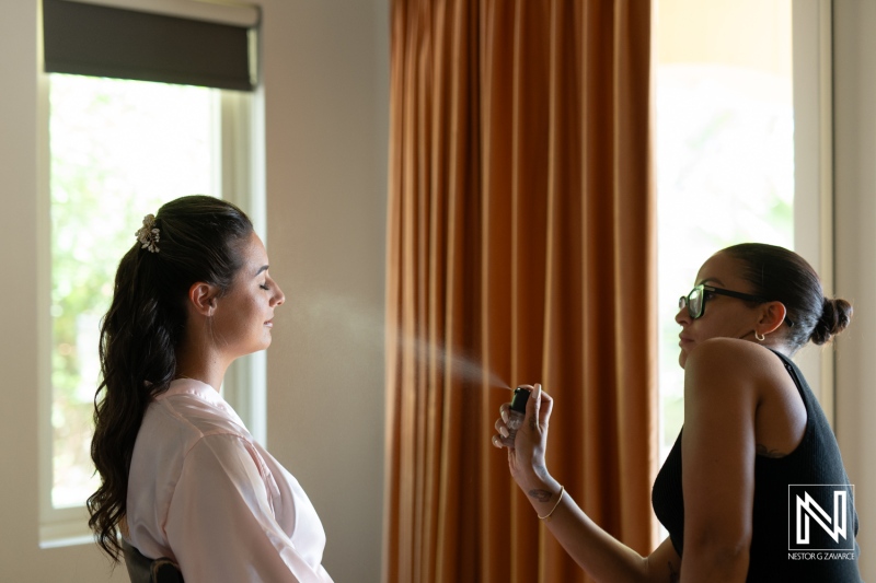 A Beauty Professional Applying Makeup to a Bride During Preparations in a Bright Room With Large Windows and Soft Curtains