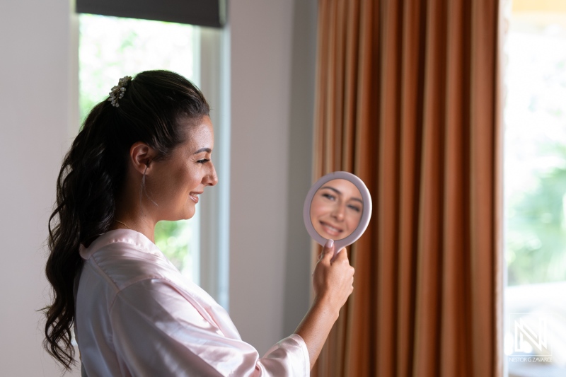 A Woman in a Silk Robe Smiles Confidently While Looking Into a Handheld Mirror in a Bright, Elegantly Decorated Room During the Early Morning